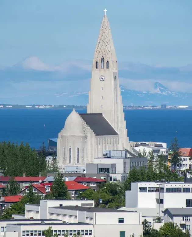 An icelandic church tower in front of an ocean and mountain backdrop